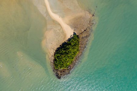 Aerial view of a small offshore island connected by a small, winding line of sand to a beautiful tropical islandの写真素材