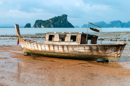 An old wooden boat on a tropical beach at sunset (Koh Yao Noi)の写真素材