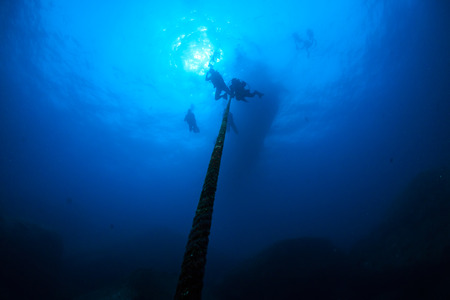 Silhouette of SCUBA divers descending into a deep oceanの写真素材