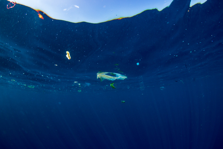 Plastic bags and debris floating on the surface of a clear, blue tropical ocean