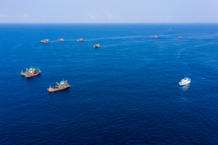 Overfishing - aerial view of a SCUBA diving boat surrounded by large industrial fishing trawlers around a conservation site in Myanmarの写真素材