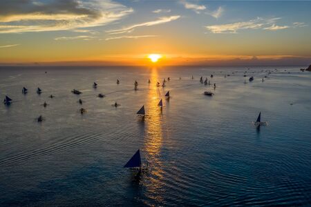 Aerial drone view of large numbers of sailboats at sunset on a tropical ocean (Boracay, Philippines)の写真素材