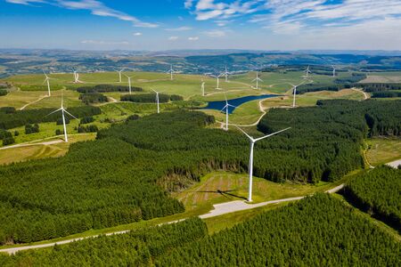 Aerial drone view of turbines at a large onshore windfarm on a green hillside (Pen y Cymoedd, Wales)の写真素材