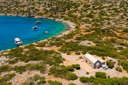 Aerial view of an old Greek church on a dry, dusty island surrounded by beautiful, deep, clear oceanの写真素材