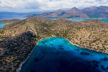 Aerial view of a clear, deep blue ocean and dry, yellow summer coastline (Kolokitha Island, Greece)の写真素材