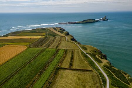 Aerial view of green fields and the ocean in Rhossili on the Gower Peninsula, Wales