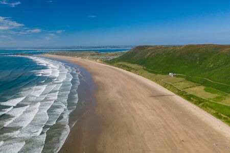 Aerial drone view of the beautiful, huge sandy beach at Rhossili on the Gower Peninsula in Wales