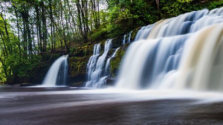 A scenic waterfall surrounded by forest in South Wales (Sgwd y Pannwr, Waterfall country, Wales)の写真素材