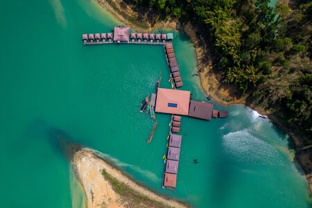 Aerial drone view of a floating wooden rafthouse surrounded by huge cliffs and tropical jungle (Khao Sok)の写真素材