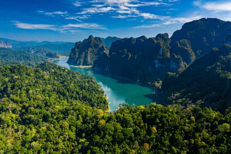 Aerial drone shot of dense tropical rainforest and towering limestone cliffs with a central lake