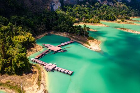 Aerial drone view of a floating wooden rafthouse surrounded by huge cliffs and tropical jungle (Khao Sok)の写真素材