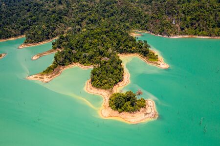 Aerial view looking downwards onto tiny islands and fingers of tropical rainforest covered land in a huge lakeの写真素材