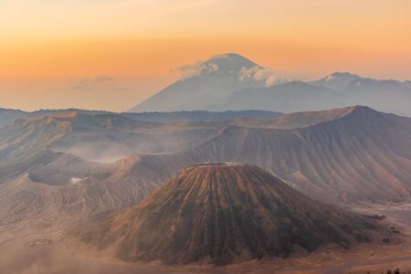 Sunrise over the Mount Bromo and Semeru volcano complex on a red, dusty morning giving the landscape...