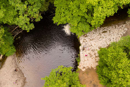 Low aerial view of a picturesque waterfall in a lush, green forest (Sgwd Gwladys, Wales, UK)