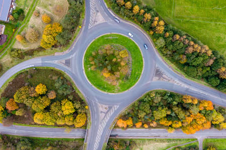 Aerial view of a traffic roundabout surrounded by trees in their autumn colours in the UKの写真素材