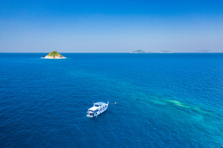 Aerial view of a SCUBA diving boat moored above a clear, tropical coral reef in Thailand's Similan Islands.のeditorial素材