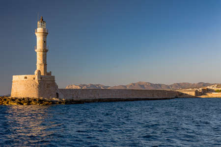 Ancient Venetian lighthouse at the old port of Chania (Crete) in the late evening sunshineの写真素材