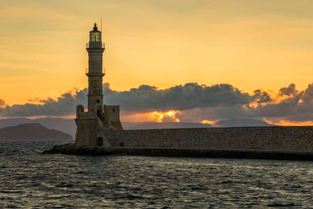 Ancient Venetian lighthouse guarding the old port of Chania, Greece at Sunsetの写真素材