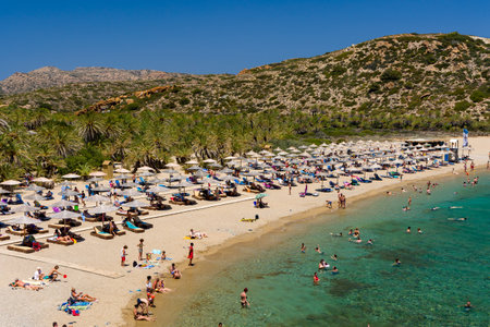 VAI, CRETE - 15 JULY 2021: Crowds of tourists on the picturesque palm fringed beach of Vai on the eastern coast of Crete (Greece)のeditorial素材