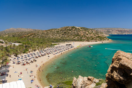 VAI, CRETE - 15 JULY 2021: Crowds of tourists on the picturesque palm fringed beach of Vai on the eastern coast of Crete (Greece)のeditorial素材