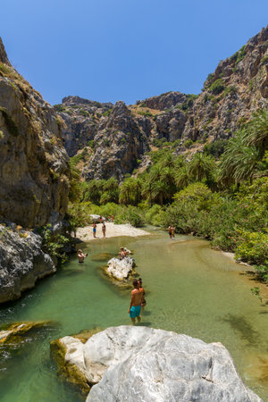 PREVELI, CRETE - JULY 21 2021: Crowds of people exploring the natural palm forest and sandy beach at Preveli on the southern coast of the Greek island of Crete.のeditorial素材