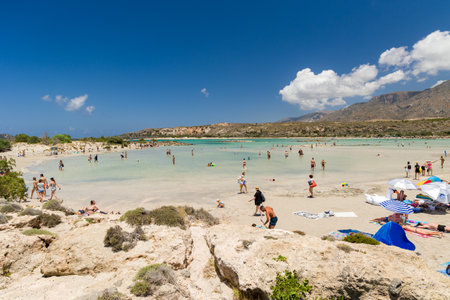 ELAFONISI, CRETE - JULY 19 2021: Crowds of tourists on the picturesque beach and shallow lagoons at Elafonissi on the Greek island of Crete.のeditorial素材