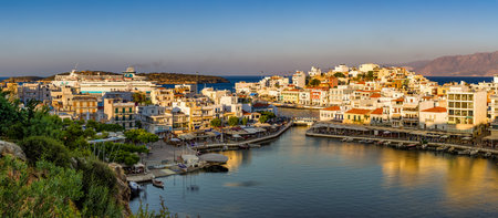 AGIOS NIKOLAOS, CRETE - 11 JULY 2021: Vouliagmeni lake and waterfront area of the town of Agios Nikolaos at sunset.  Crete, Greece.のeditorial素材