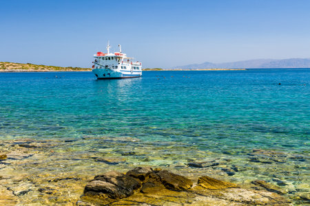 ELOUNDA, CRETE - 16 JULY 2021: Groups of tourists swim around and depart a busy day cruise boat near the town of Elounda in Crete, Greece.のeditorial素材