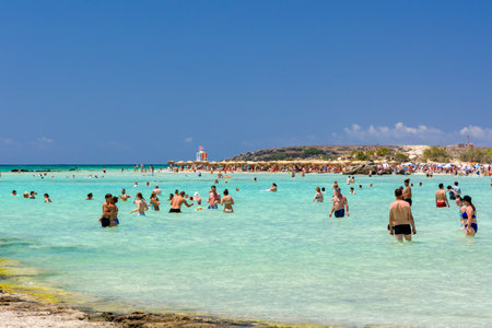 ELAFONISI, CRETE - JULY 19 2021: Crowds of tourists on the picturesque beach and shallow lagoons at Elafonissi on the Greek island of Crete.のeditorial素材