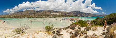 ELAFONISI, CRETE - JULY 19 2021: Crowds of tourists on the picturesque beach and shallow lagoons at Elafonissi on the Greek island of Crete.のeditorial素材