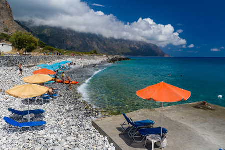 AGIA ROUMELLI, CRETE - 20 JULY 2021: Tourists relaxing on the rocky beach in the village of Agia Roumelli near the exit of the Samaria Gorge on the island of Creteのeditorial素材