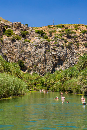 PREVELI, CRETE - JULY 21 2021: Crowds of people exploring the natural palm forest and sandy beach at Preveli on the southern coast of the Greek island of Crete.のeditorial素材