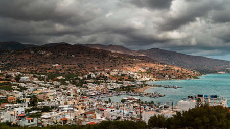 Stormy clouds and bands of rain over the Greek tourist resort town of Elounda on the island of Crete.の写真素材