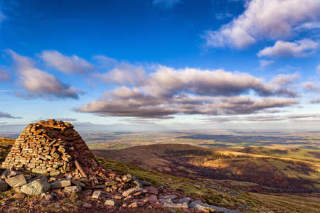 A small hilltop cairn overlooking rural farmland and hills (Carn Pica, Brecon Beacons,Wales)の写真素材