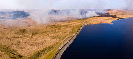 Aerial view of a huge wildfire on higher level moorland next to a reservoir (Llangynidr Moors, Wales)の写真素材