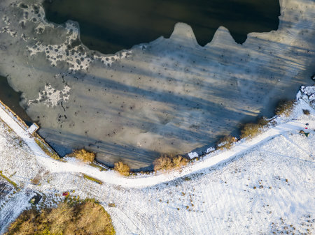 Top down aerial view of ice forming on a freezing lake surrounded by snow (Wales)の写真素材
