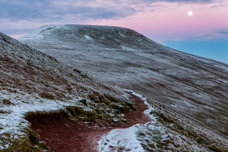 A cold, frosty mountain top with full moon behind (Pen-y-Fan, Brecon Beacons, Wales)