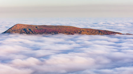 Mountain top rising above a sea of fog at dusk (Skirrid Fawr, Wales)の写真素材