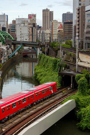 TOKYO, JAPAN - AUGUST 09 2023: Trains passing a busy intersection and tunnel over the Kanda River at the Hijiribashi Bridge, Tokyo, Japanのeditorial素材