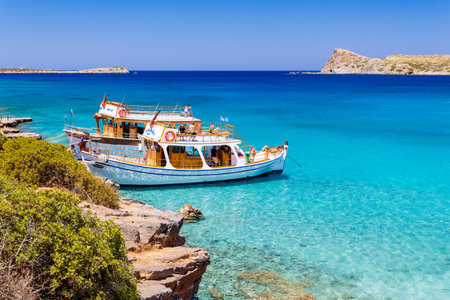 CRETE, GREECE - JULY 12 2023: Large boats full of tourists exploring the clear waters and hot, dry coastline in Kolokitha, near Elounda, Creteのeditorial素材