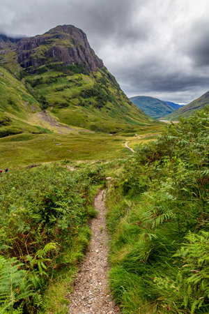 Rugged mountain scenery under a damp, grey, stormy sky (Glen Coe, Highlands, Scotland)の写真素材