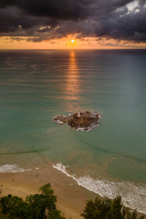 Aerial view of a stormy, tropical sunset behind a small lighthouse and tropical beachの写真素材