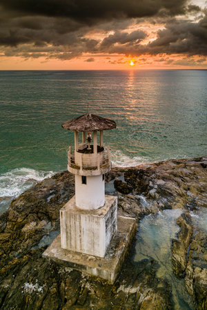 Aerial view of a stormy, tropical sunset behind a small lighthouse and tropical beachの写真素材