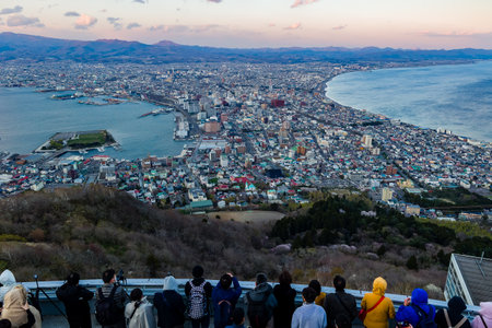 HAKODATE, JAPAN - APRIL 23 2023: Crowds of tourists on Mount Hakodate overlooking the city of Hakodate on the northern Japanese island of Hokkaido at sunsetのeditorial素材