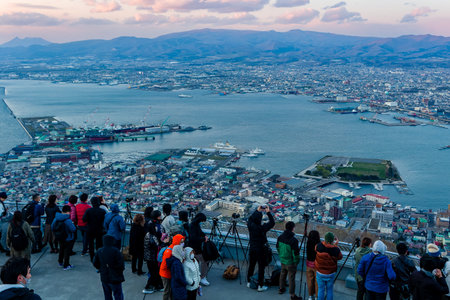 HAKODATE, JAPAN - APRIL 23 2023: Crowds of tourists on Mount Hakodate overlooking the city of Hakodate on the northern Japanese island of Hokkaido at sunsetのeditorial素材