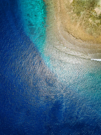 Top down aerial view of blue water and a tropical coral reef in a warm oceanの写真素材