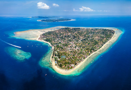 Aerial view of a tiny tropical island surrounded by large, fringing coral reef and blue, warm ocean (Gili Air, Lombok, Indonesia)の写真素材