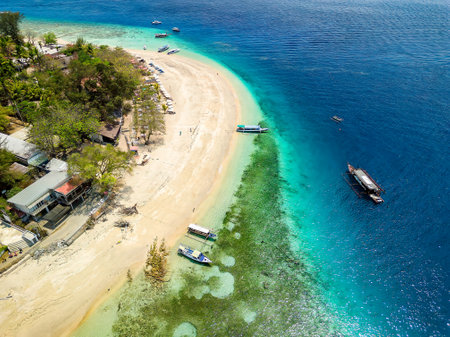Lines of traditional wooden boats on the beach of a small tropical island surrounded by coral reef (Gili Air, Indonesia)の写真素材
