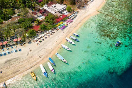 Birds eye view of colorful sun umbrellas and boats on a small, warm tropical beachの写真素材