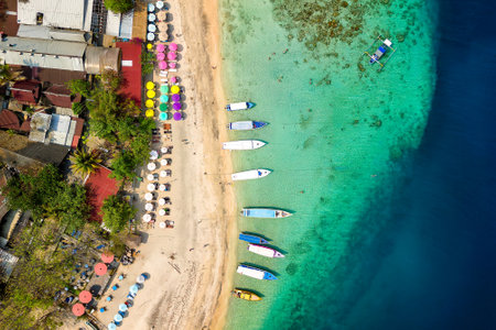 Top down view of colorful sunshades and tourist boats on a tropical beachの写真素材